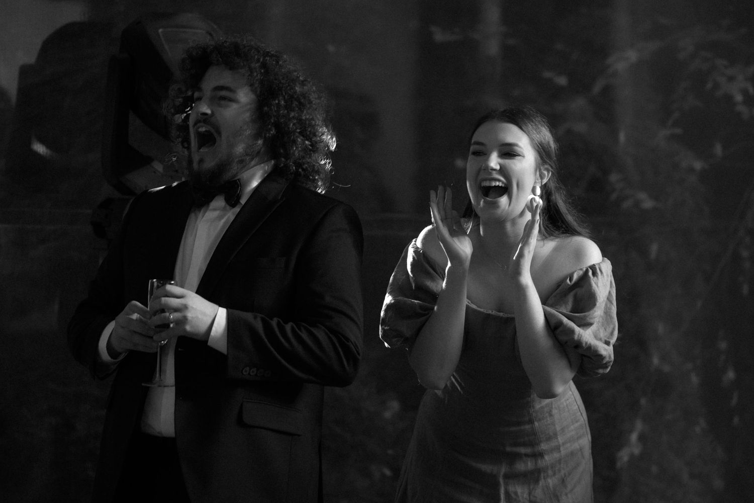 Black and white photo of two performers singing passionately on stage with dramatic lighting and smoke effects.