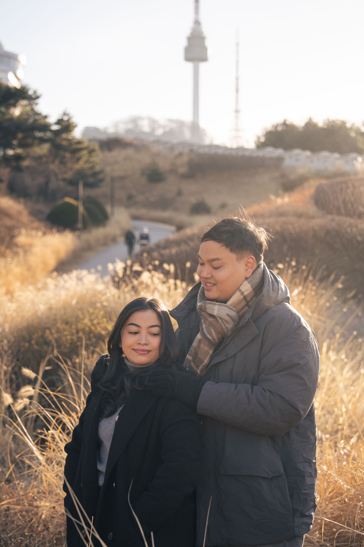 A couple shares an intimate moment together in a golden field during sunset.