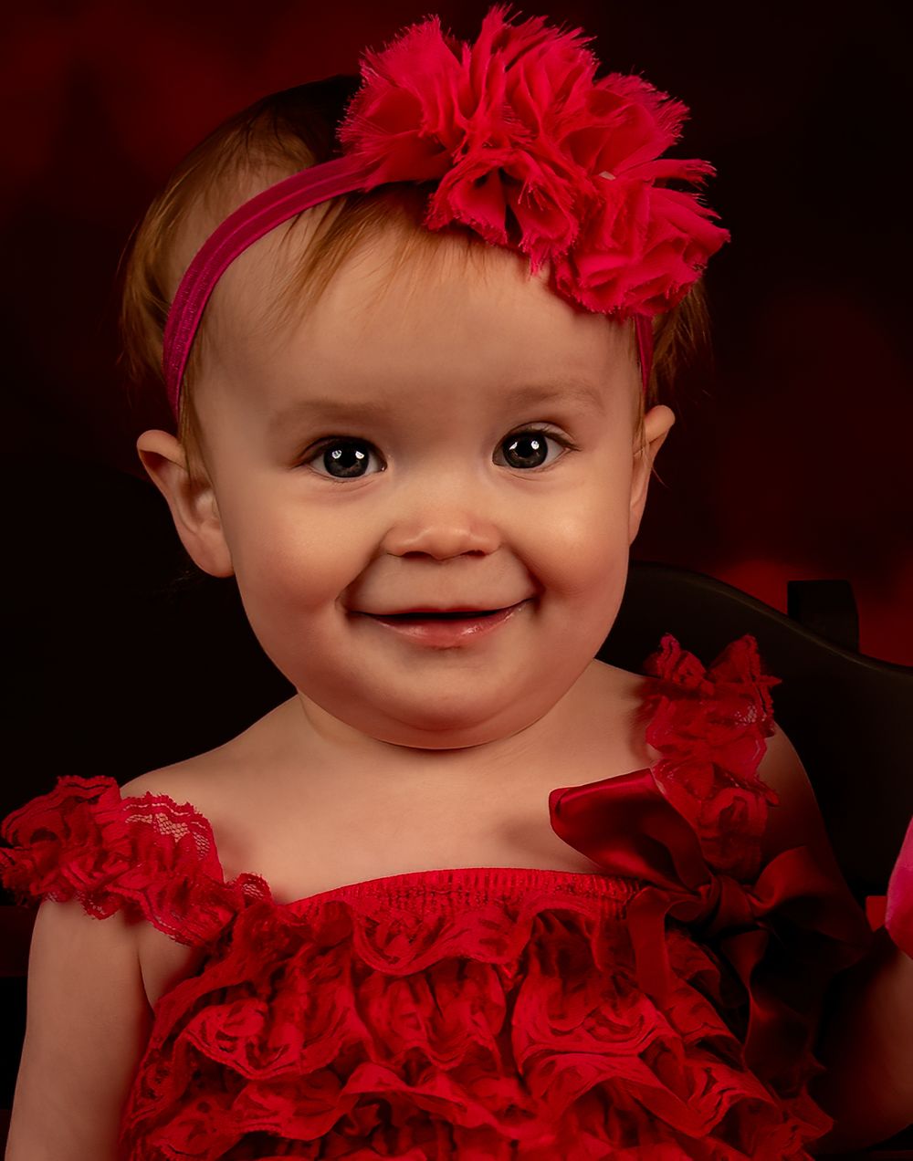 A series of photos showing a baby in a red ruffled dress and red flower headband against a dark background.