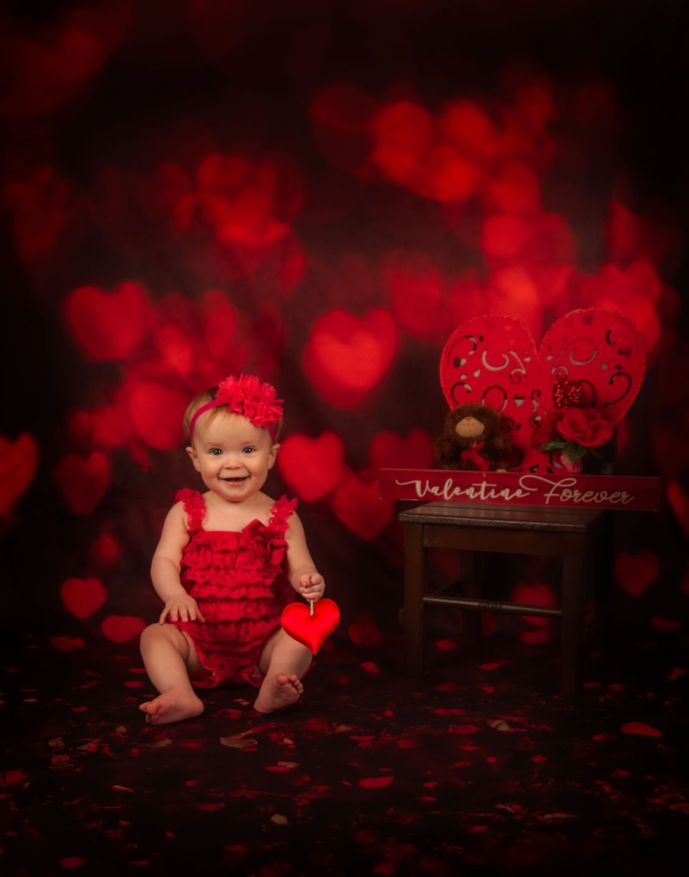 Valentine's Day photo setup with dramatic red heart bokeh lighting and dark background creates a romantic atmosphere.