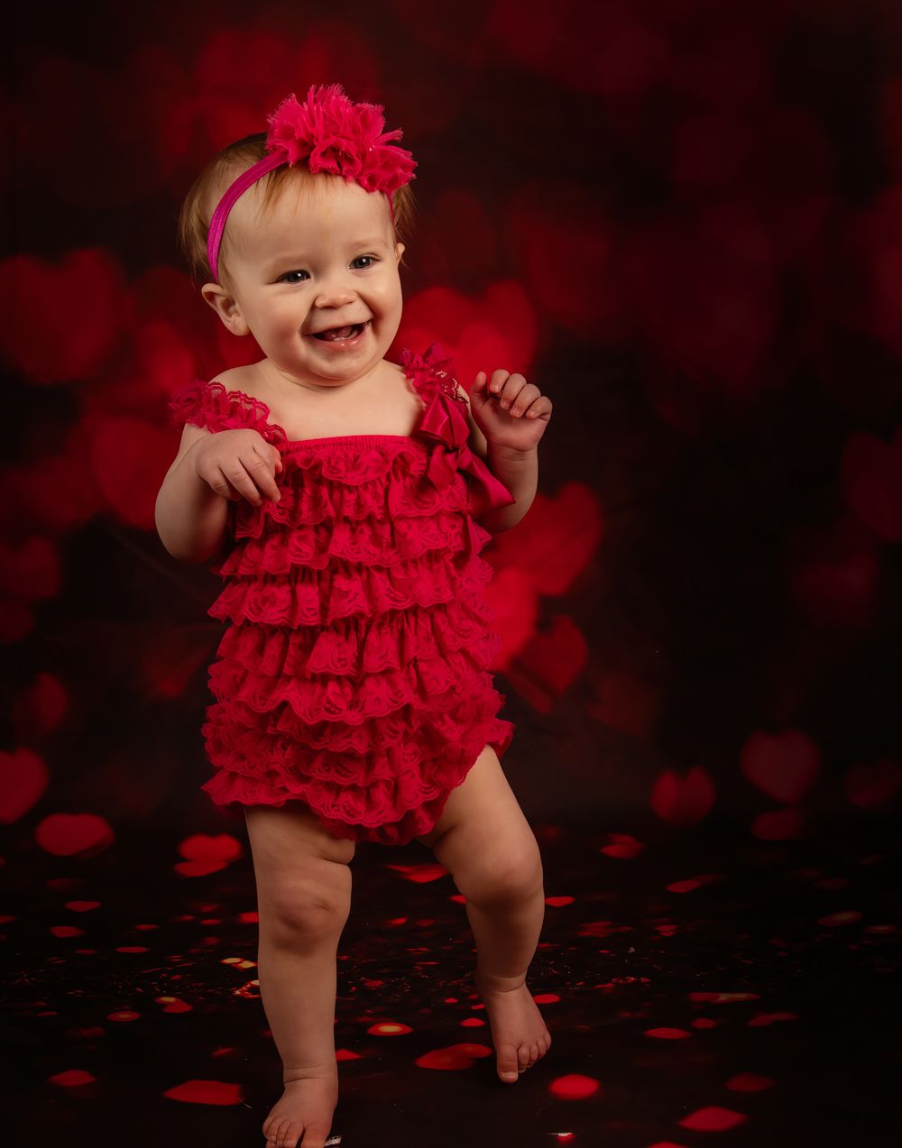 A red ruffled romper outfit photographed in a romantic Valentine's themed setting.