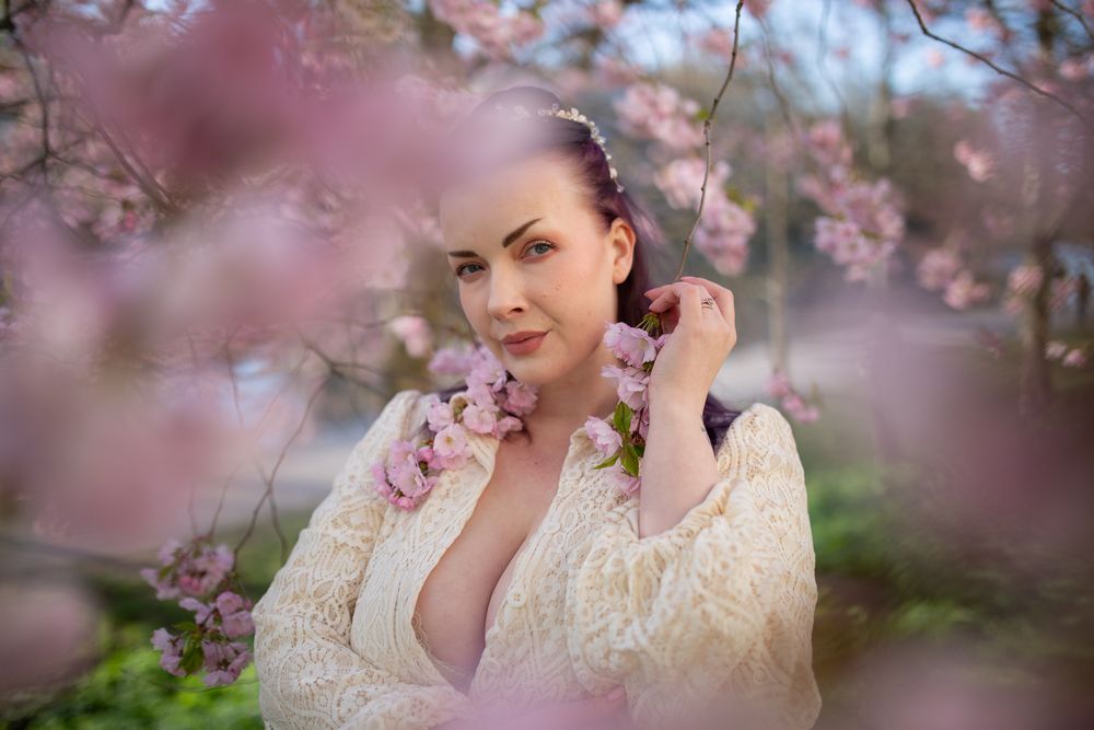 Boudoir -kuva ulkona kirsikankukkien keskellä
