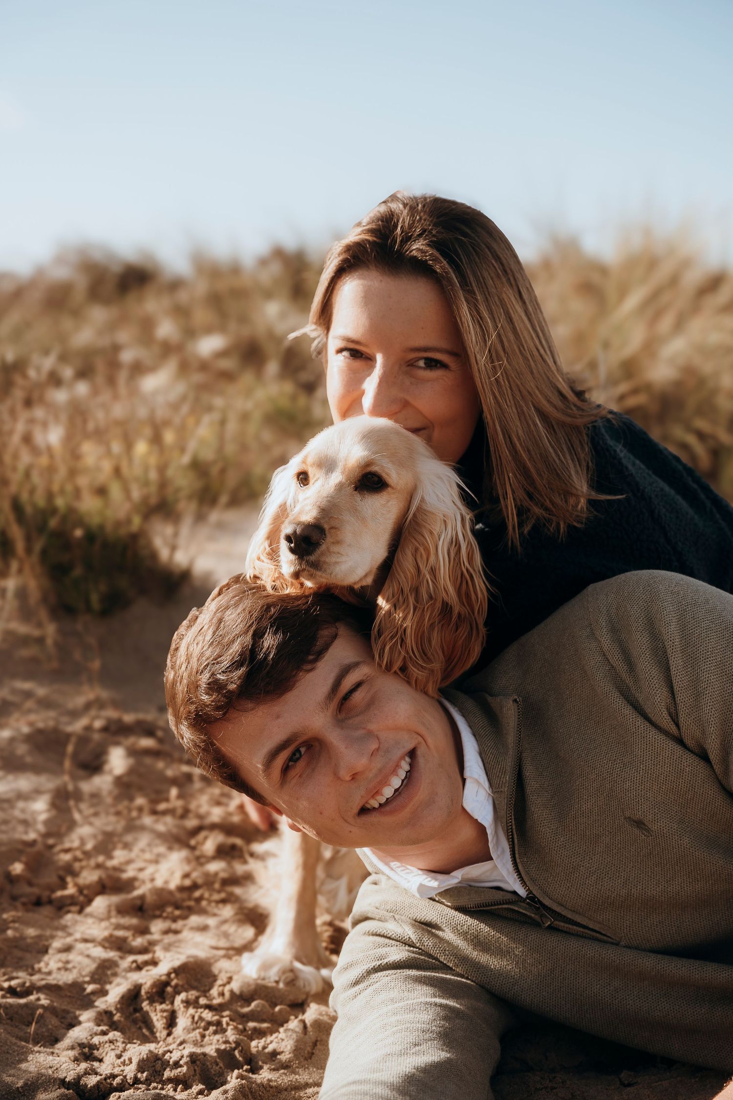 A casual family stroll through a sun-drenched autumn field with rolling hills in the background.
