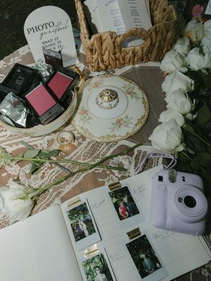 Vintage floral plates and photo booth pictures displayed on an elegant wedding guestbook table.