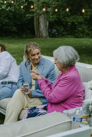 Two people share a tender moment on an outdoor bench while enjoying drinks and conversation together.