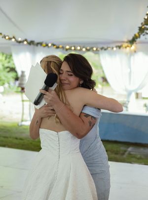 A slow dance moment captured under twinkling lights at an outdoor wedding reception.