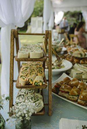 Tiered wooden display of appetizers and finger foods at wedding reception.