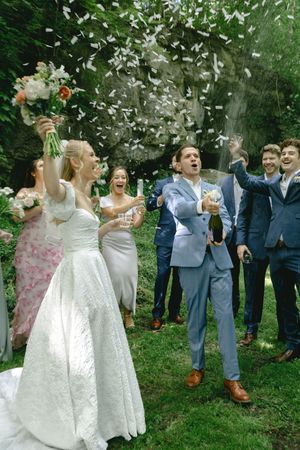 Wedding celebration with confetti toss in a wooded garden setting.