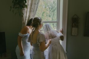 Natural light streams through window as wedding preparations take place indoors.