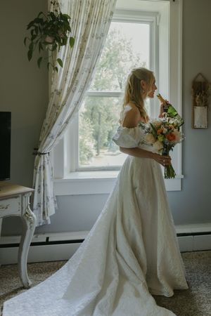 Wedding dress preparation scene by a bright window with flowing white gown and curtains.
