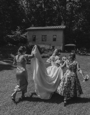 Group dancing together outdoors in vintage-style floral dresses and white garments on a sunny summer day.