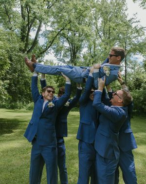 Group in navy blue suits performs synchronized celebratory toast outdoors in a garden setting.