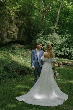 A wedding couple poses in a lush green garden setting with a flowing white dress.