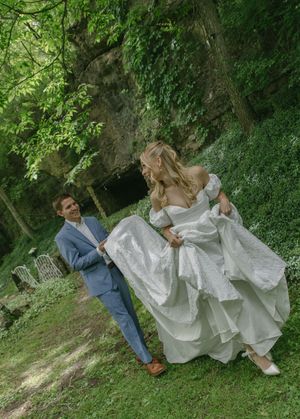A playful wedding photoshoot in a green garden setting with flowing white dress.