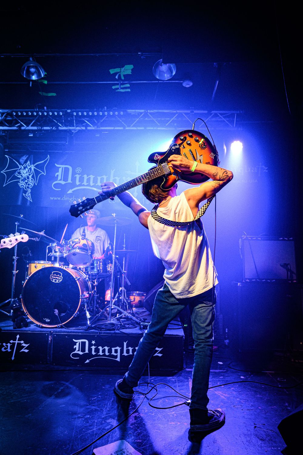 A musician performs on stage with dramatic blue lighting during a concert at a rock venue.