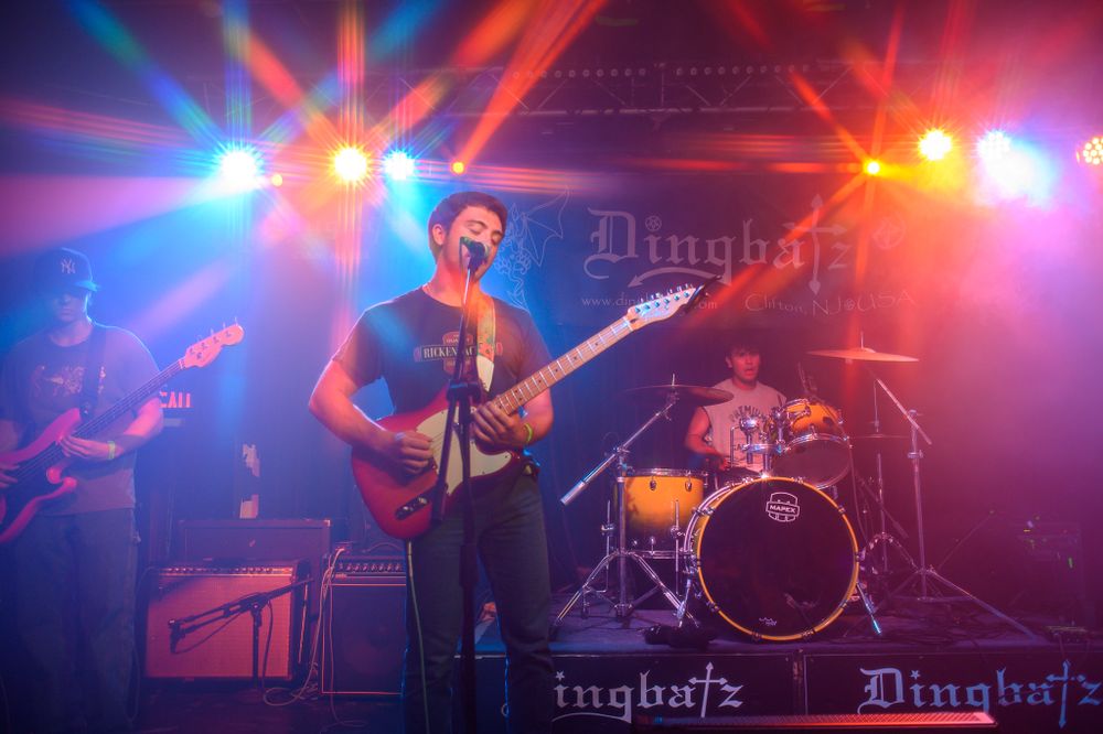 Rock band performs on stage with colorful blue and red lighting effects at a concert venue.