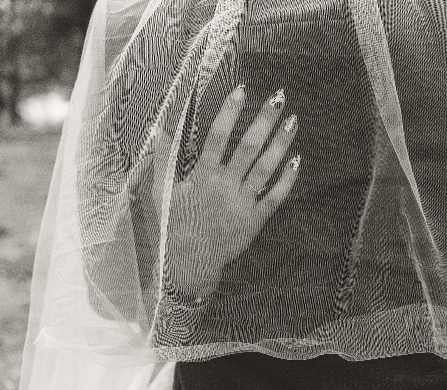 Details in black and white showing cow print nails and wedding ring.
