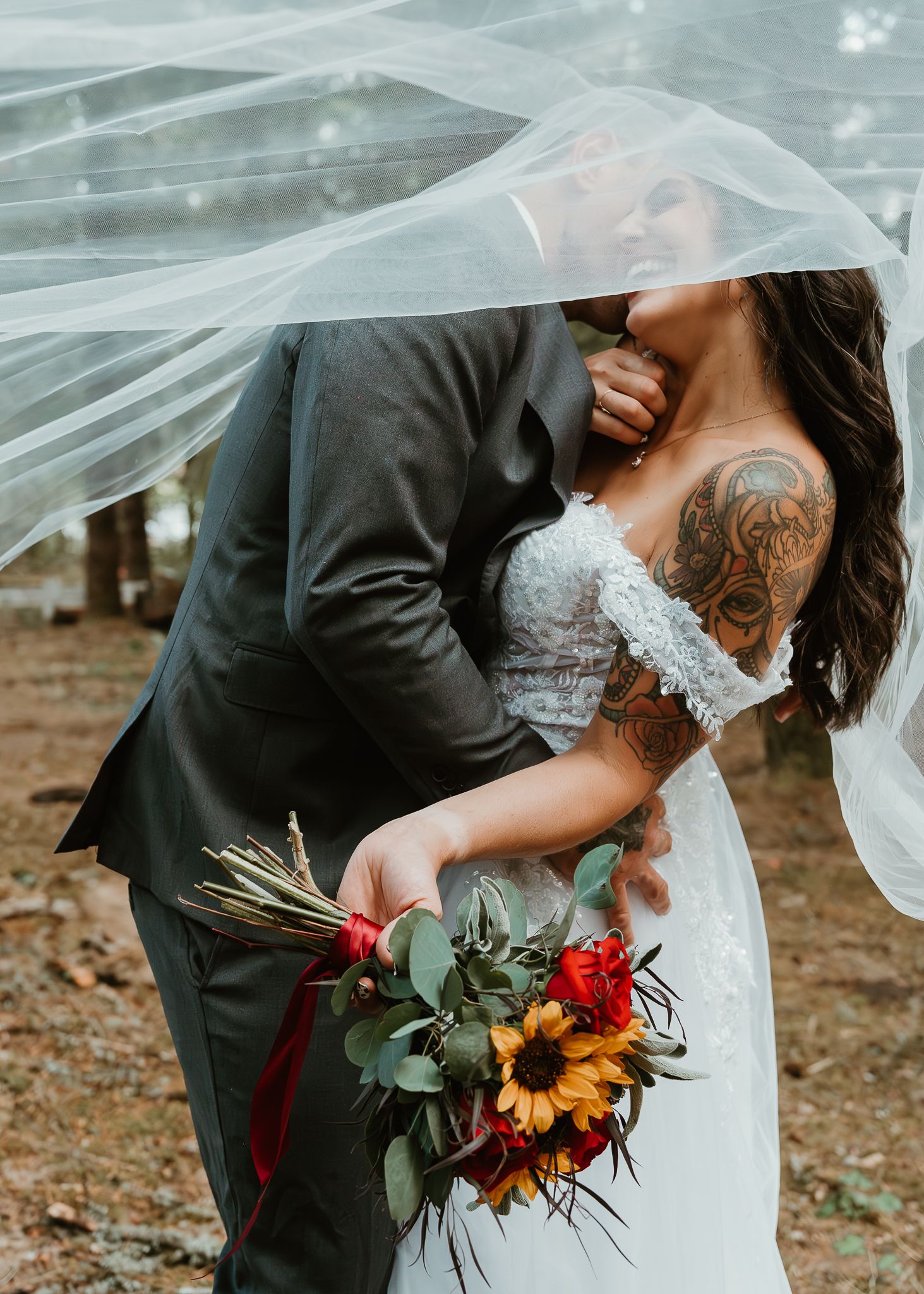 Iconic under the veil shot with groom kissing neck.