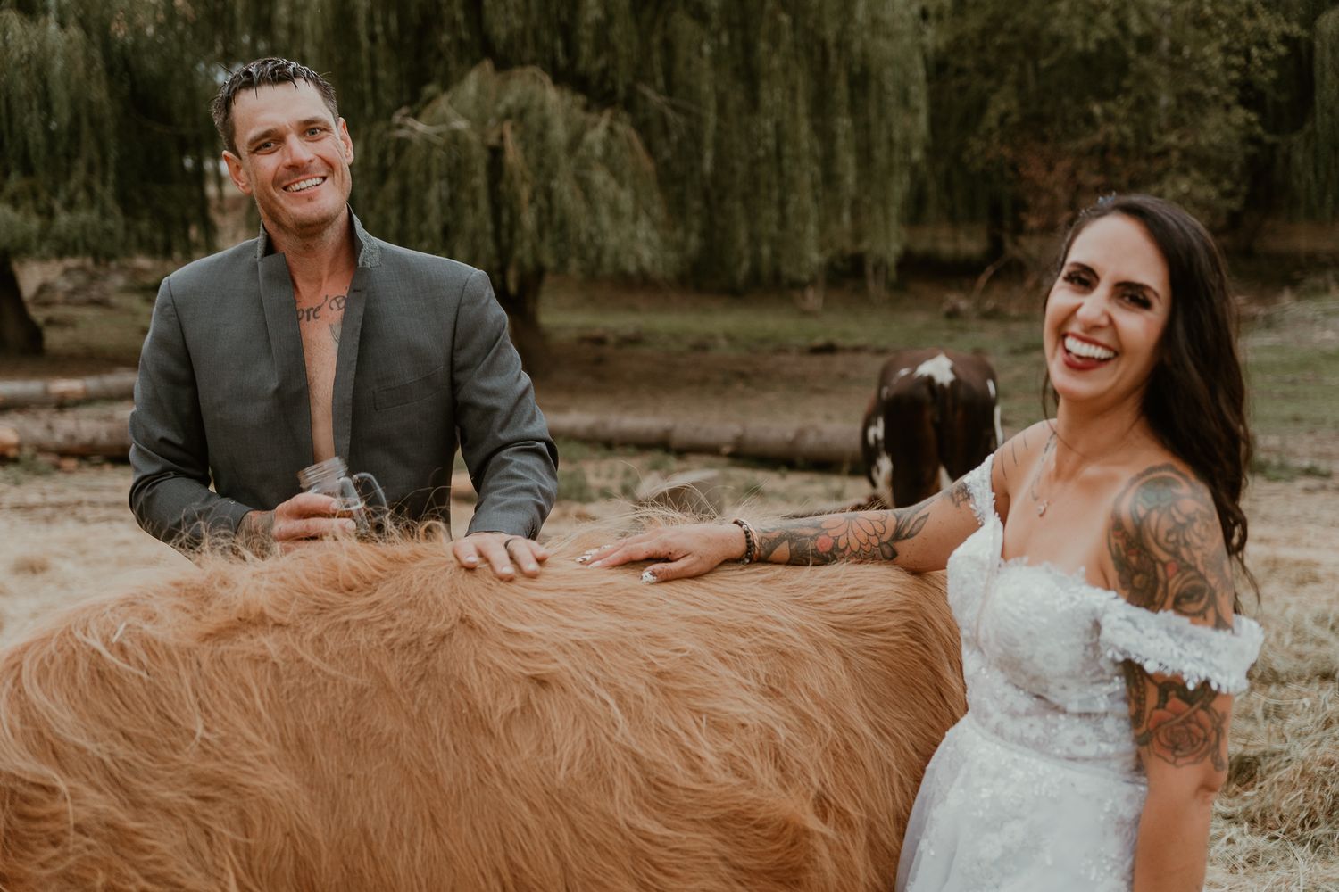 Couple/owners smiling at camera with highland cow.