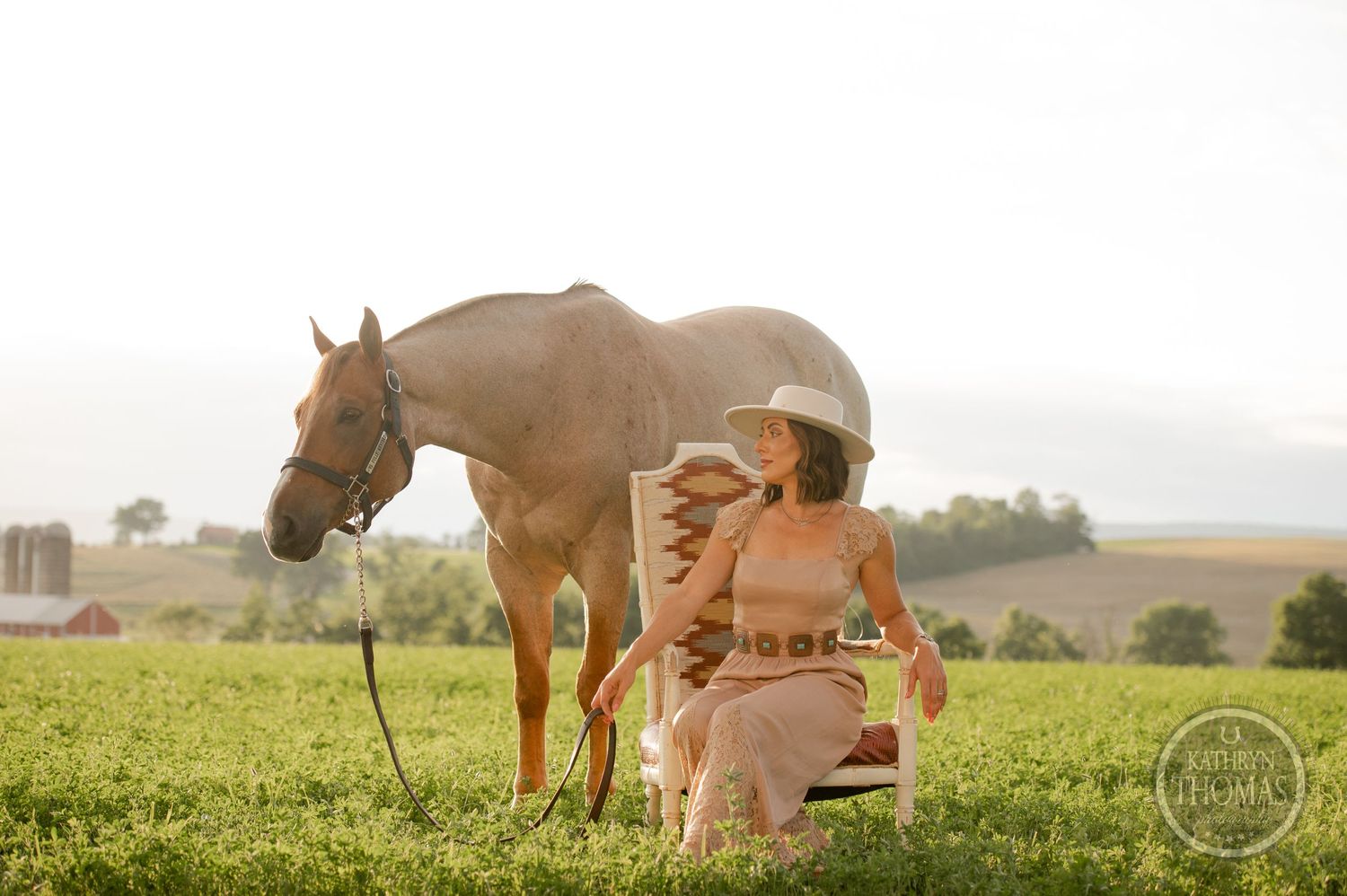 Horse and rider sit together during golden hour in a lush green field with a dreamy vintage aesthetic.