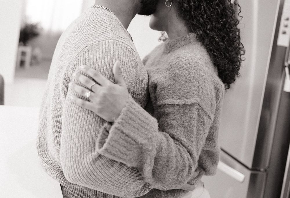 Intimate black and white photo of couple in sweaters embracing.