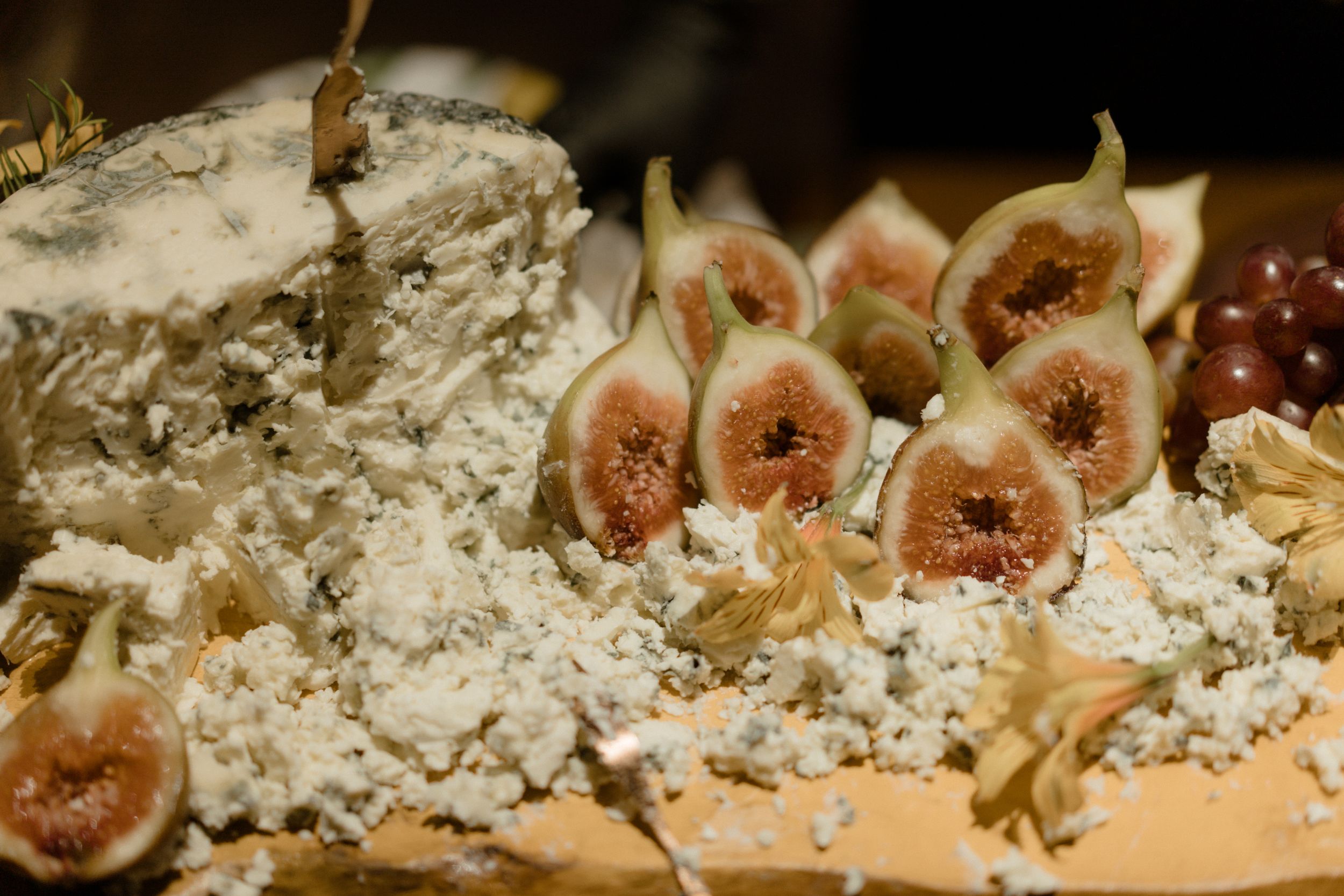 Fresh figs arranged on a rustic wooden board with crumbled cheese.