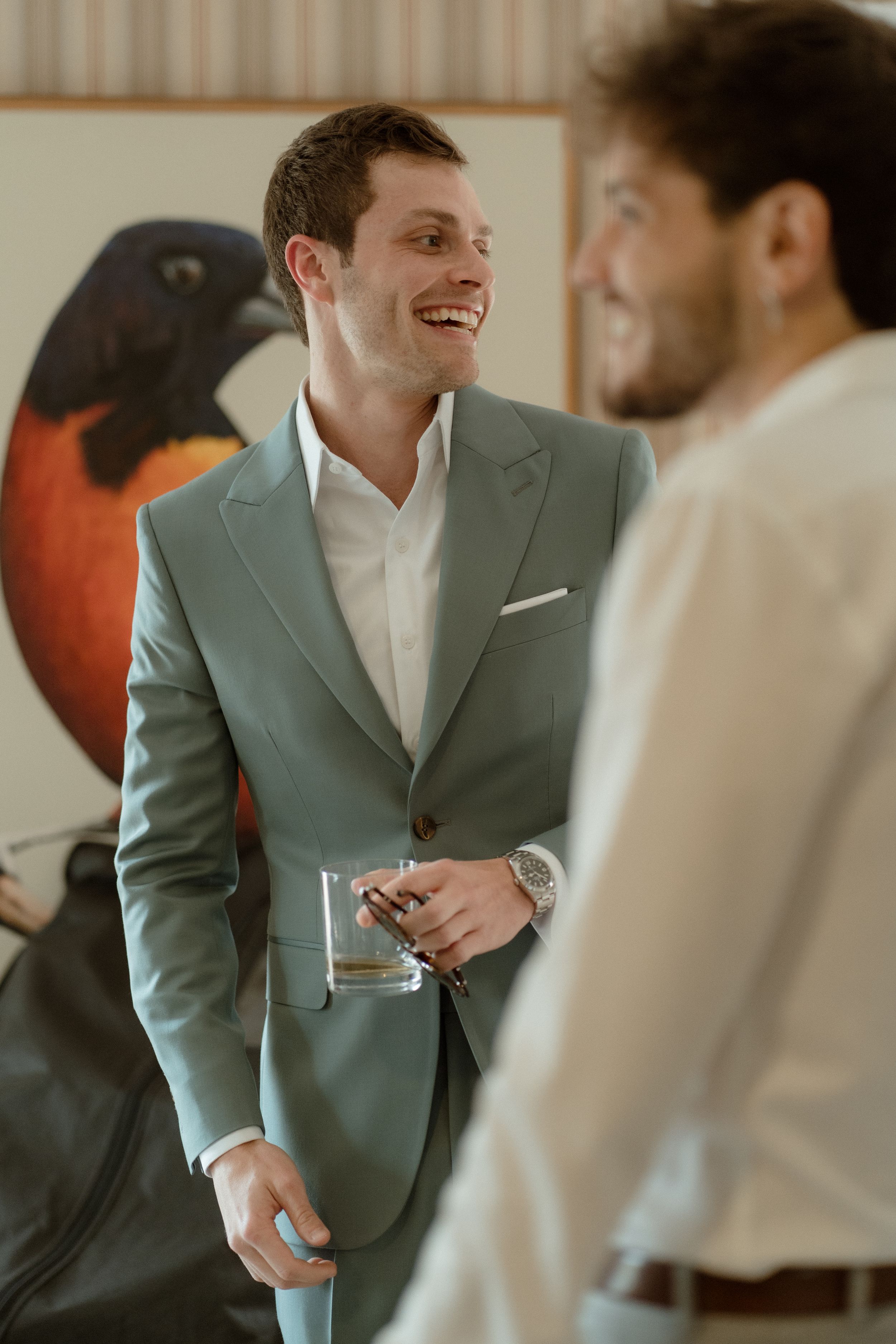 Candid moment in front of modern art piece wearing sage green suit.