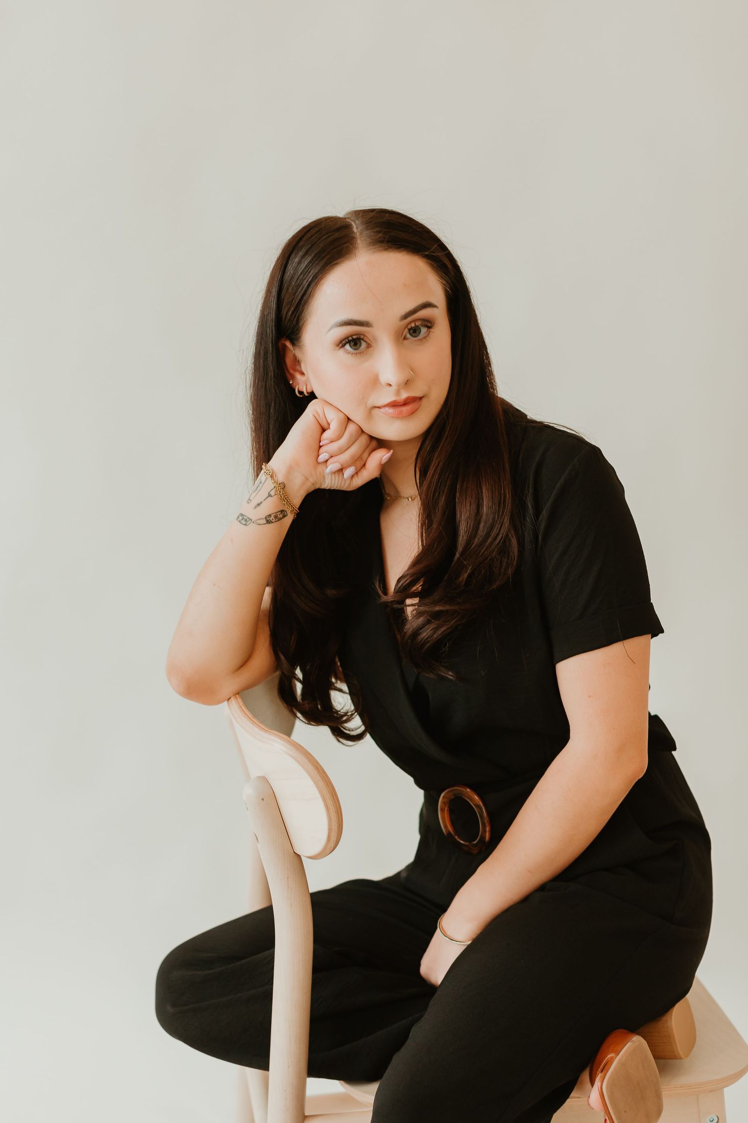 Minimalist studio portraits on light background showing contemplative poses in black clothing.