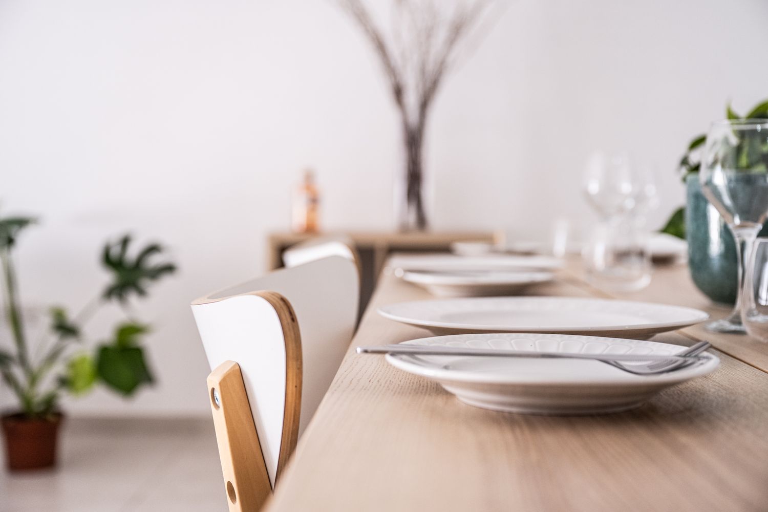 Clean minimalist table setting with white plates and natural decor elements.