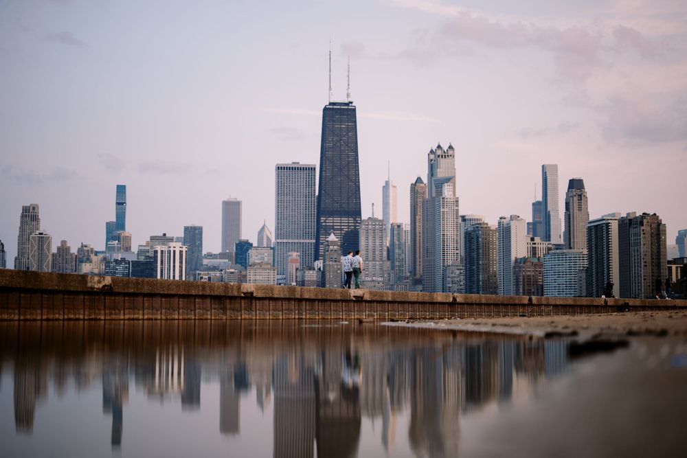 Chicago skyline reflecting in Lake Michigan at dusk with John Hancock Center and other iconic skyscrapers.