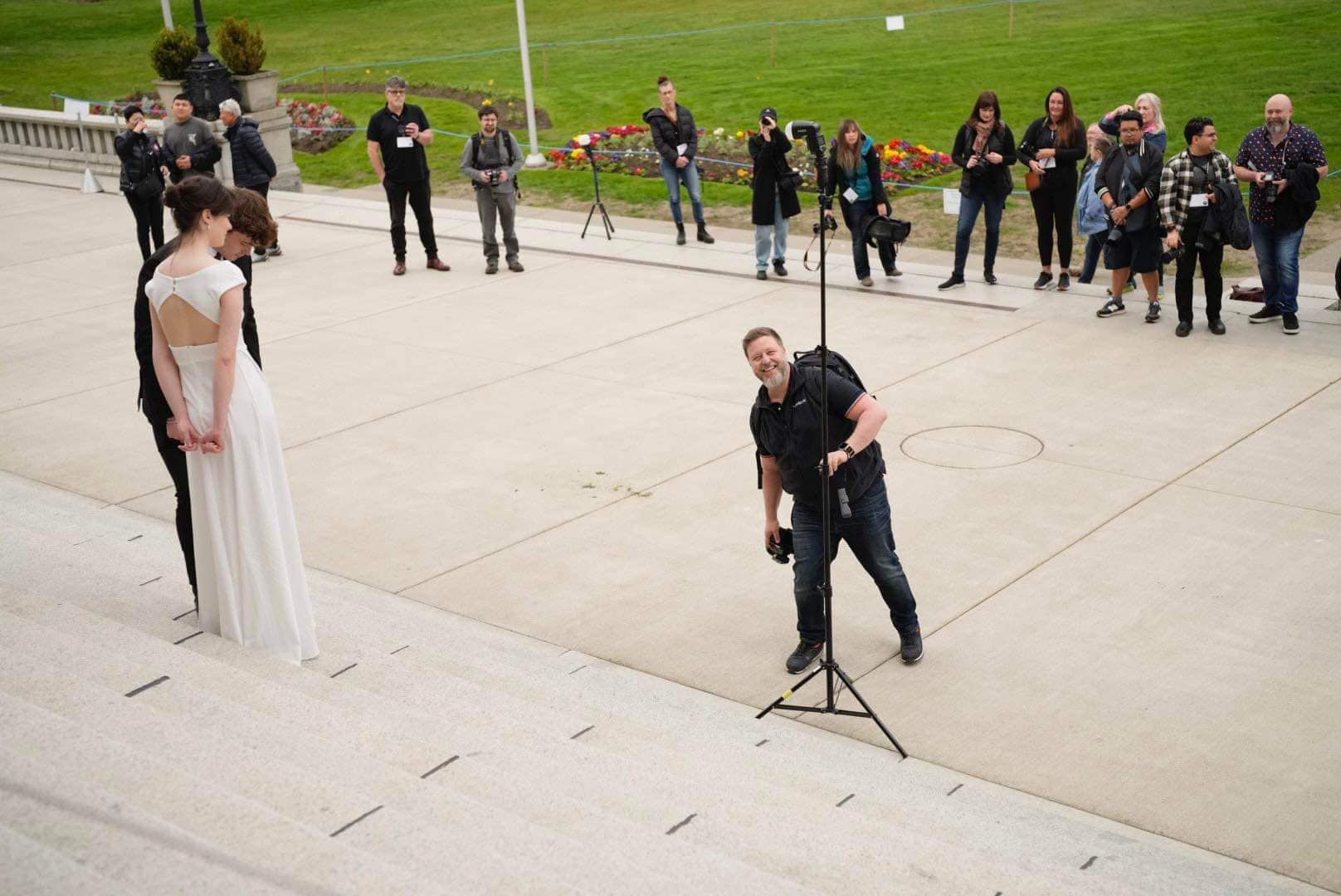 Professional photographer capturing a wedding scene on outdoor steps with onlookers.