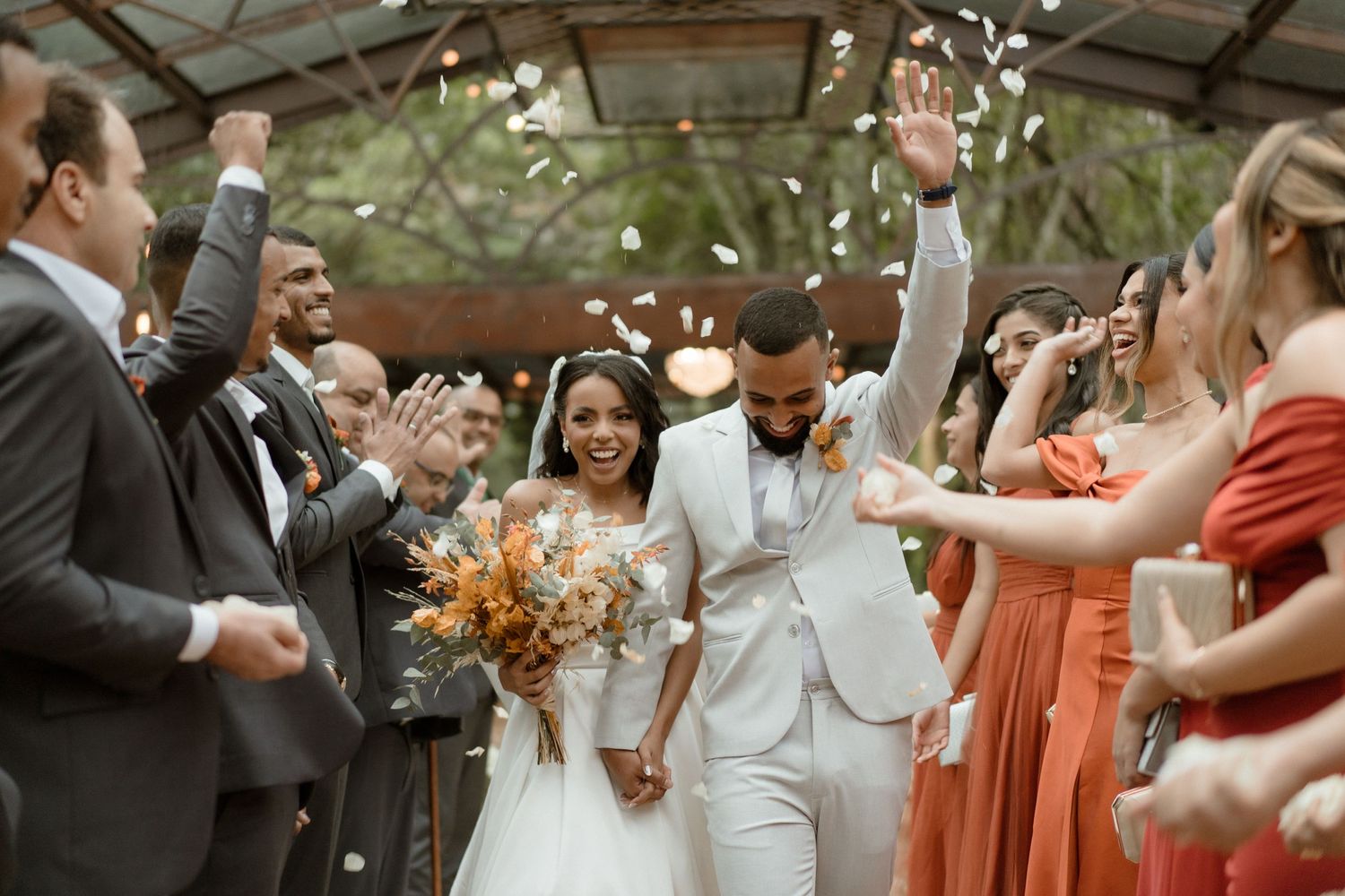 Wedding celebration with bridesmaids in coral dresses dancing joyfully at outdoor reception.