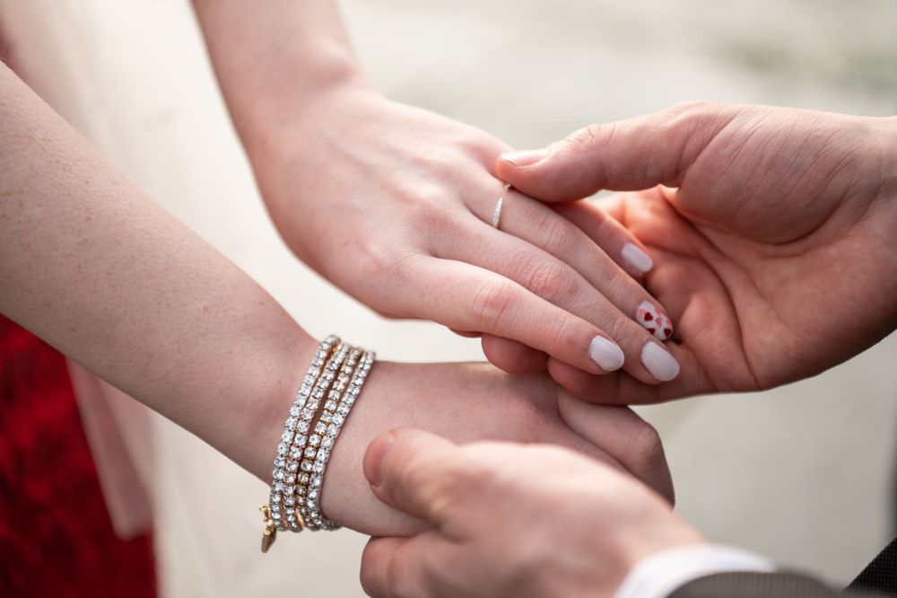 Close-up of hands exchanging rings during wedding ceremony with elegant crystal bracelet in view.