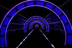 Abstract neon blue and purple circular patterns create a futuristic technological design against a black background.