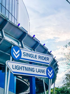 Blue and white Lightning Lane sign mounted on a building facade with themed architectural details at Disney theme park.