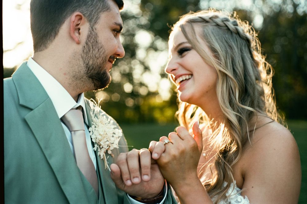 Candid wedding photo showing couple laughing together in golden evening light.