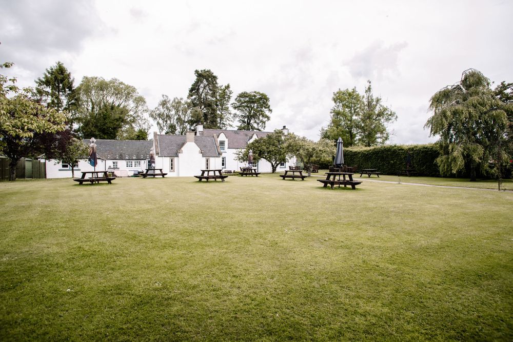Row of white teepees set up on a grassy field with picnic tables for an outdoor event.