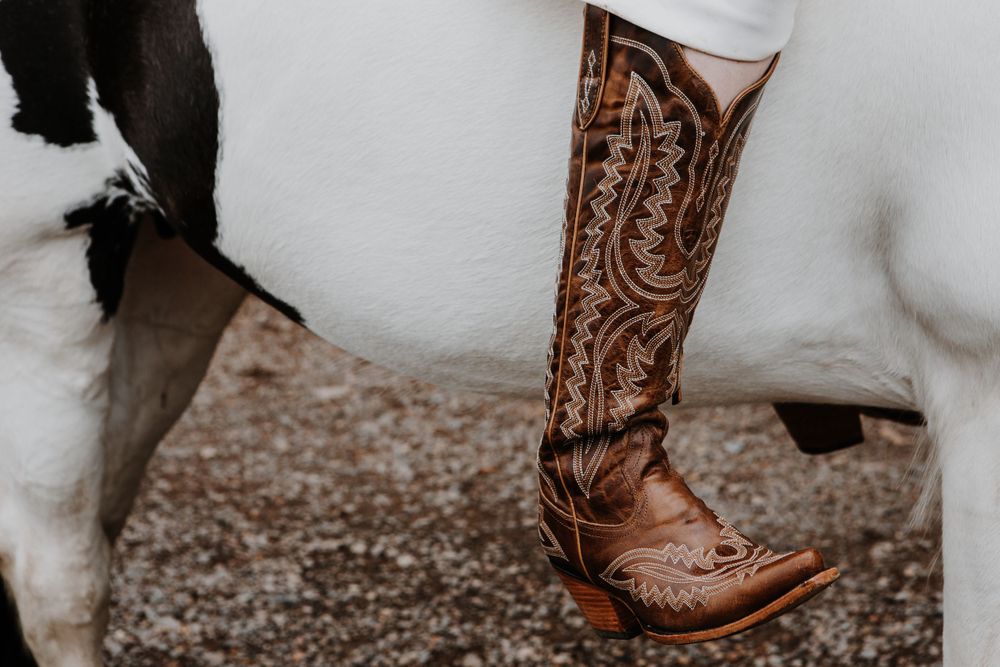 Detailed brown leather cowboy boot with intricate western stitching and designs shown against a light background.