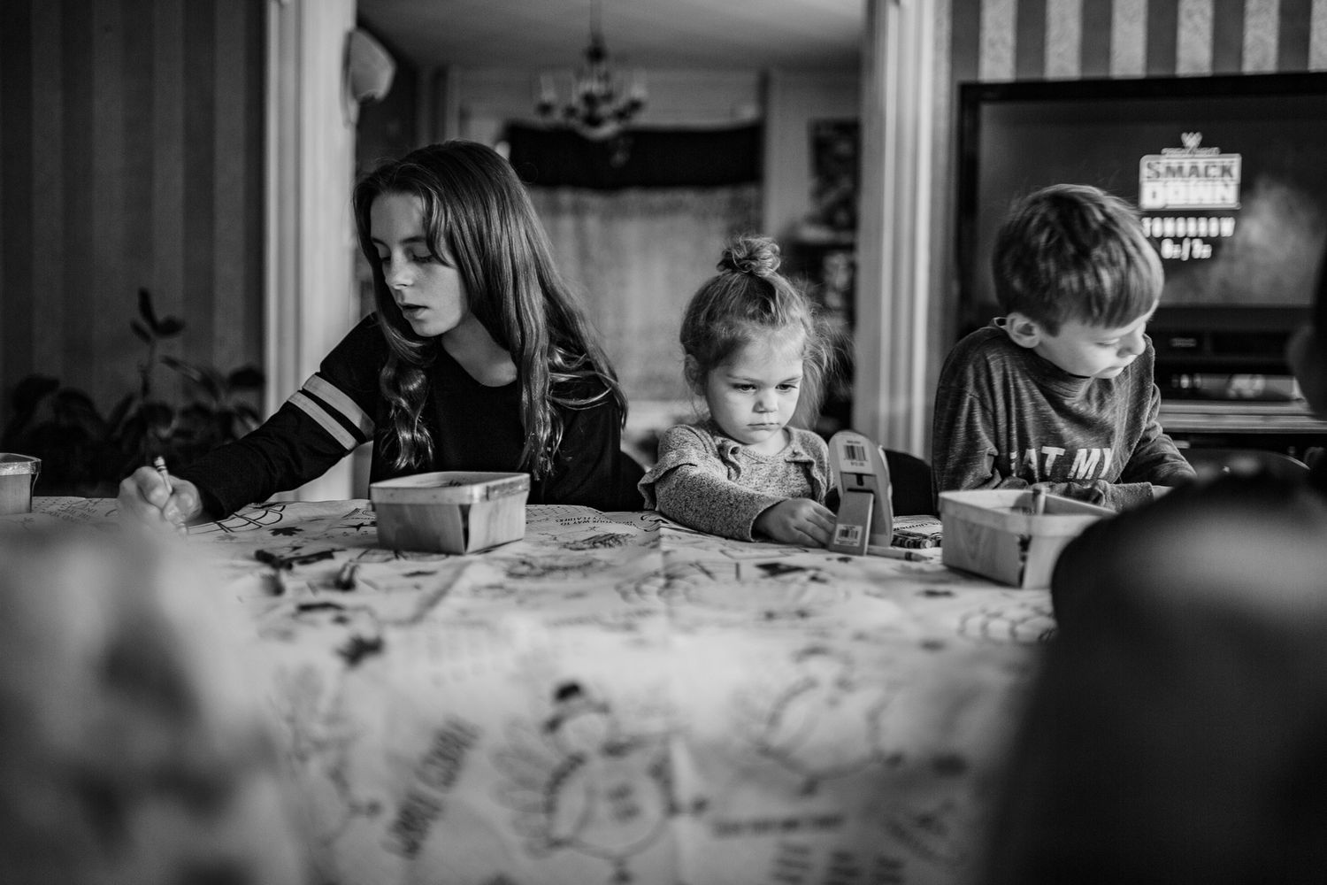 People sit at a table working on crafts together in black and white photograph.