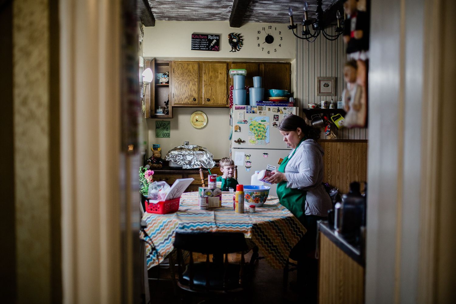 Someone creates food in a busy home kitchen with wooden cabinets and various cooking supplies and utensils.