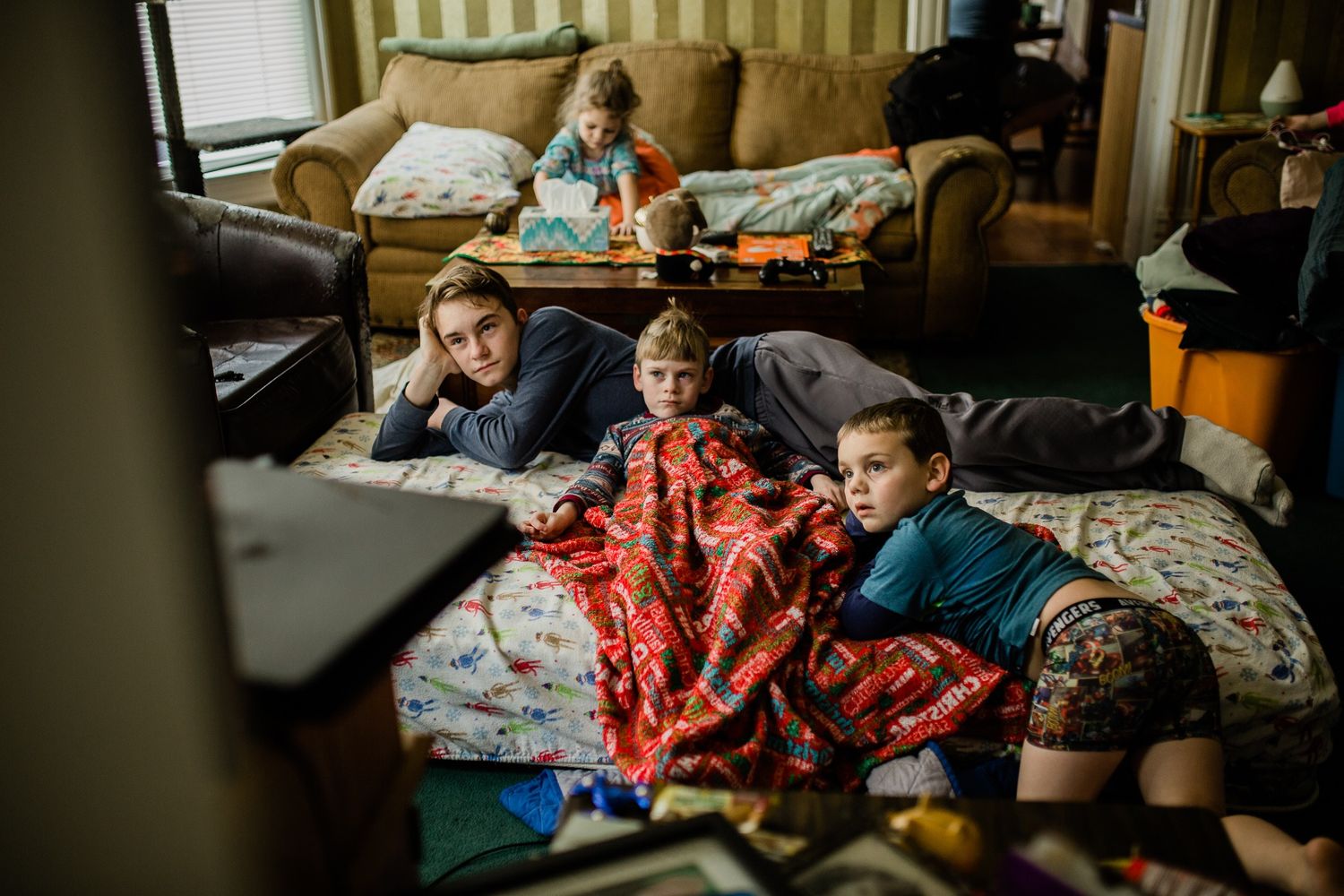 Children relaxing and watching television while lounging on blankets in a cozy living room.
