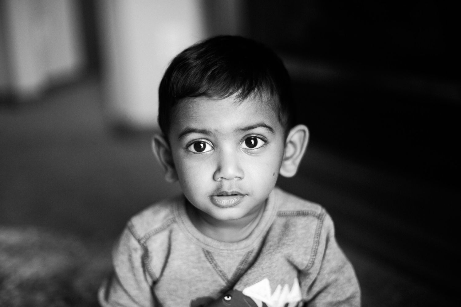 Black and white portrait of a child with wide eyes looking directly at the camera.