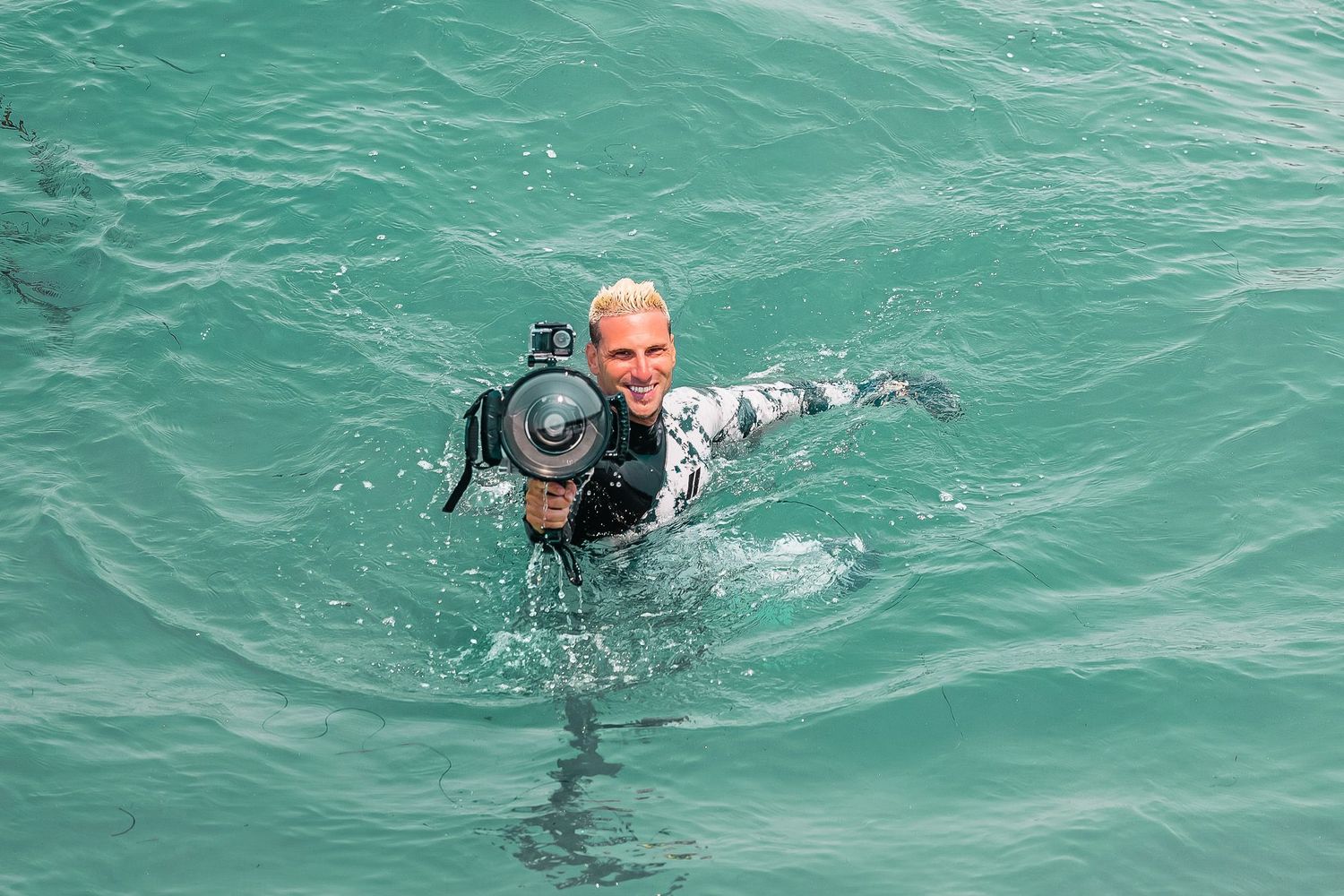 San Diego surf photographer Steve swimming in the ocean while holding a professional underwater camera housing setup.