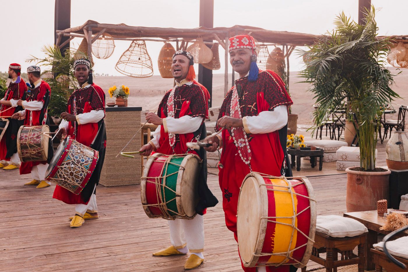 Traditional musicians in red costumes perform with drums during a cultural celebration.