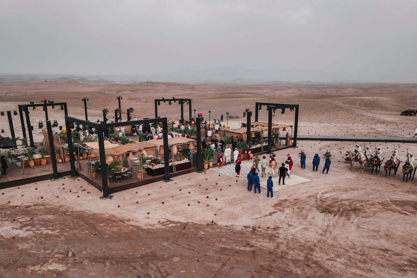 Desert dining setup with decorative tables and lanterns as visitors gather for an outdoor experience.