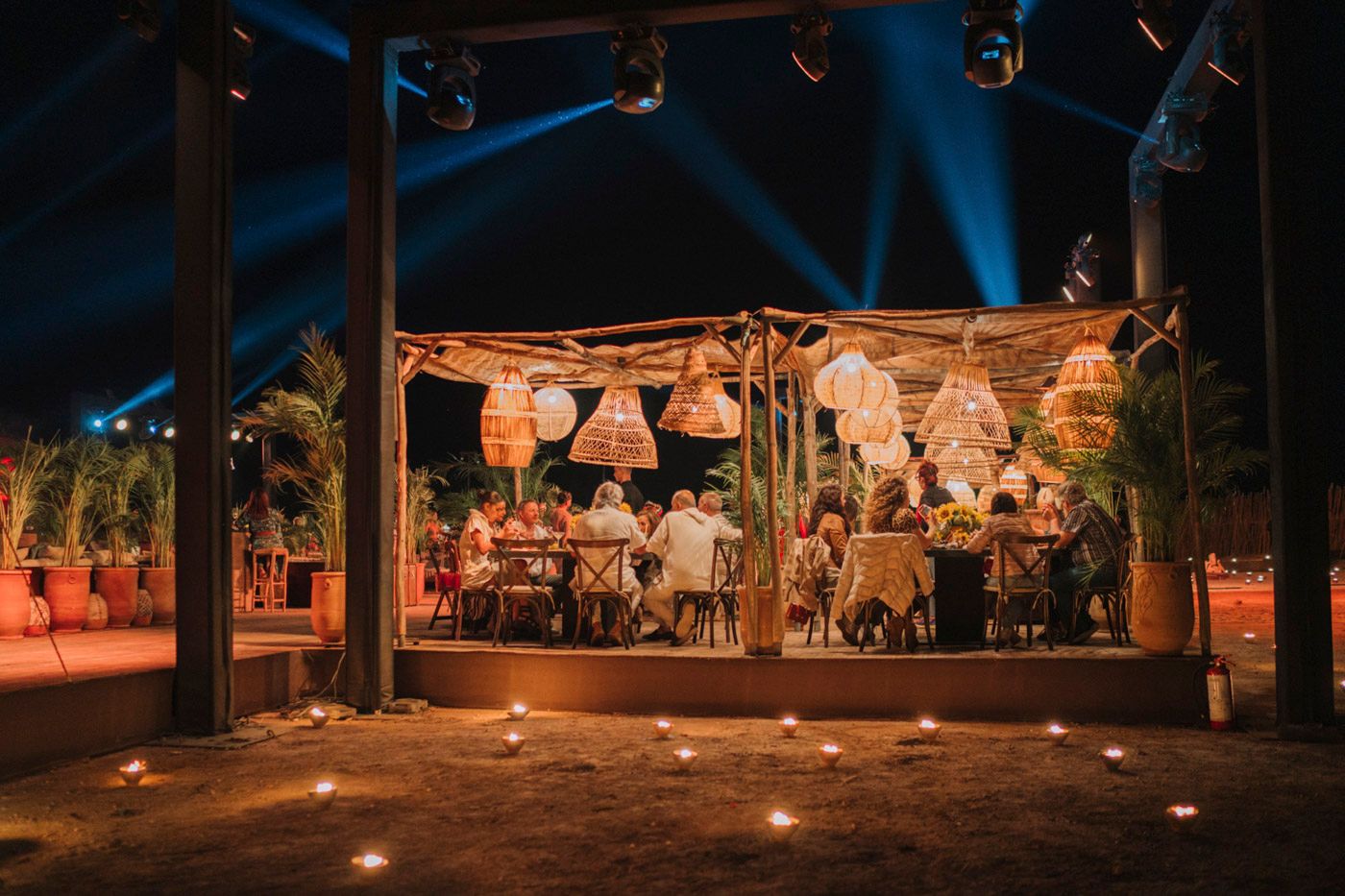 Outdoor wedding reception under rustic wooden beams with warm lighting and lanterns creating a romantic ambiance.
