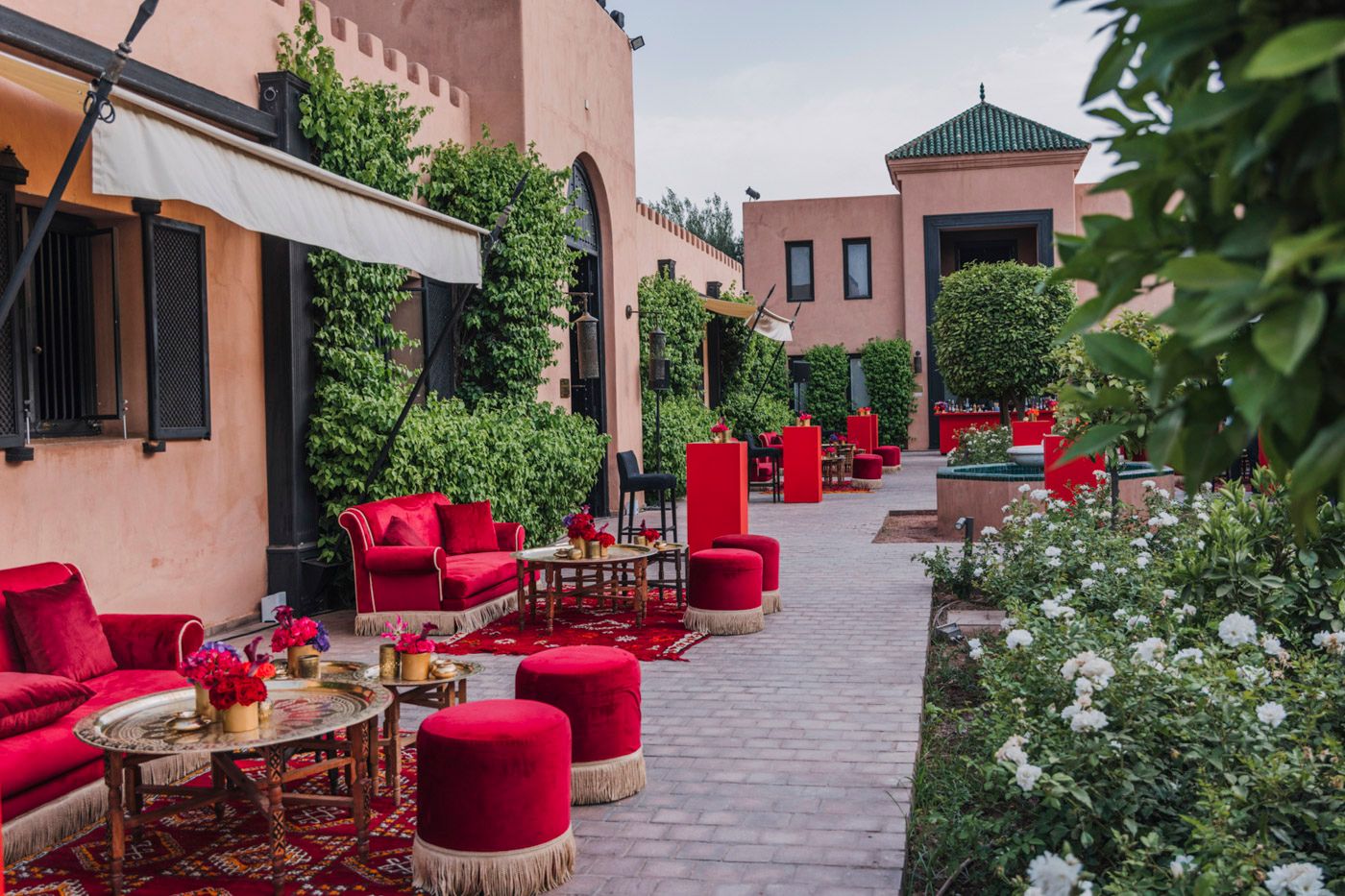Luxurious outdoor patio with vibrant red velvet seating and lush greenery at a Mediterranean-style villa.