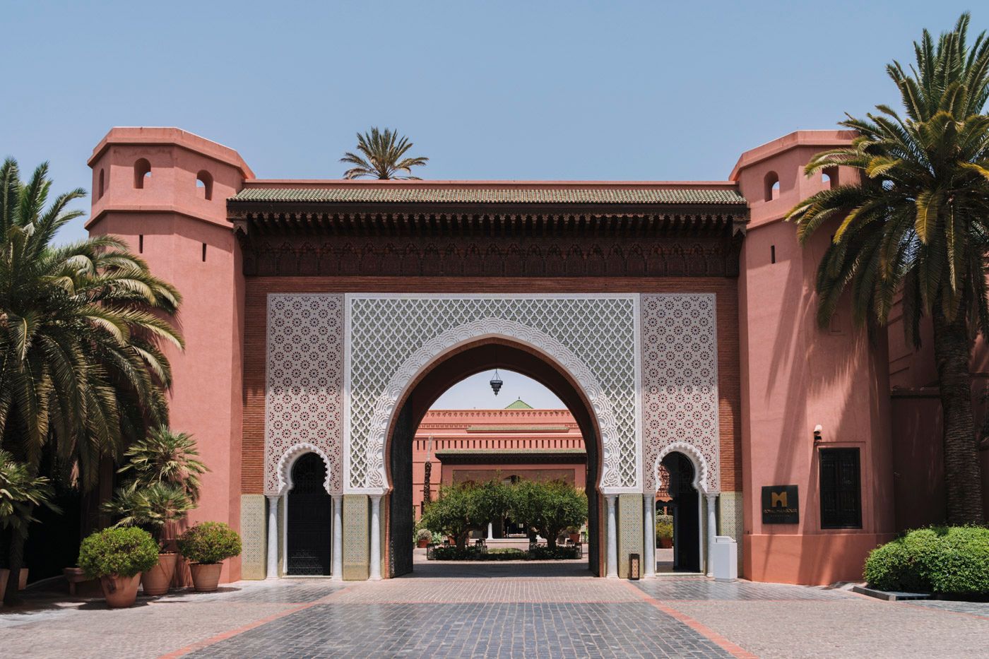 Pink archway entrance gate with Moroccan architectural details and palm trees at a luxury resort in Morocco.