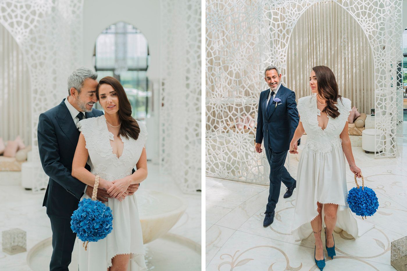 Couple celebrates their wedding day in an elegant white interior with vibrant blue floral bouquet accents.