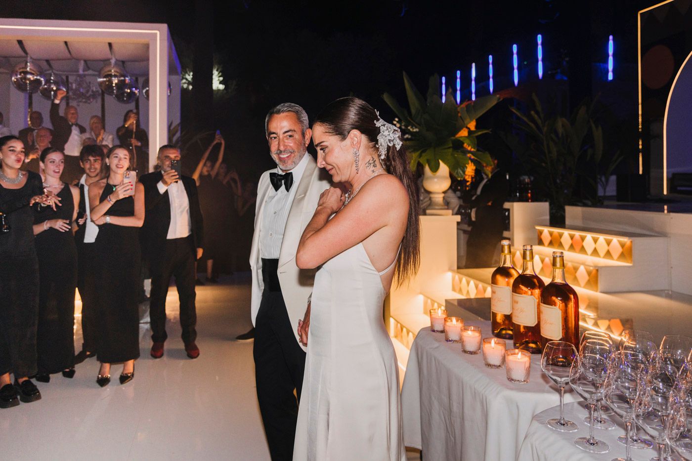 A formal wedding reception with guests gathered around a candlelit table display at an evening celebration.